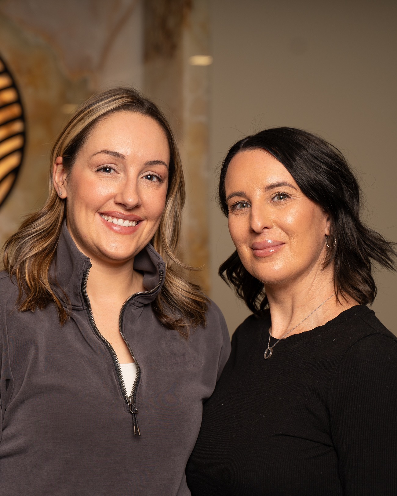 A member of the Refined by Glacial Sands team smiling in front of the practice's illuminated stone emblem