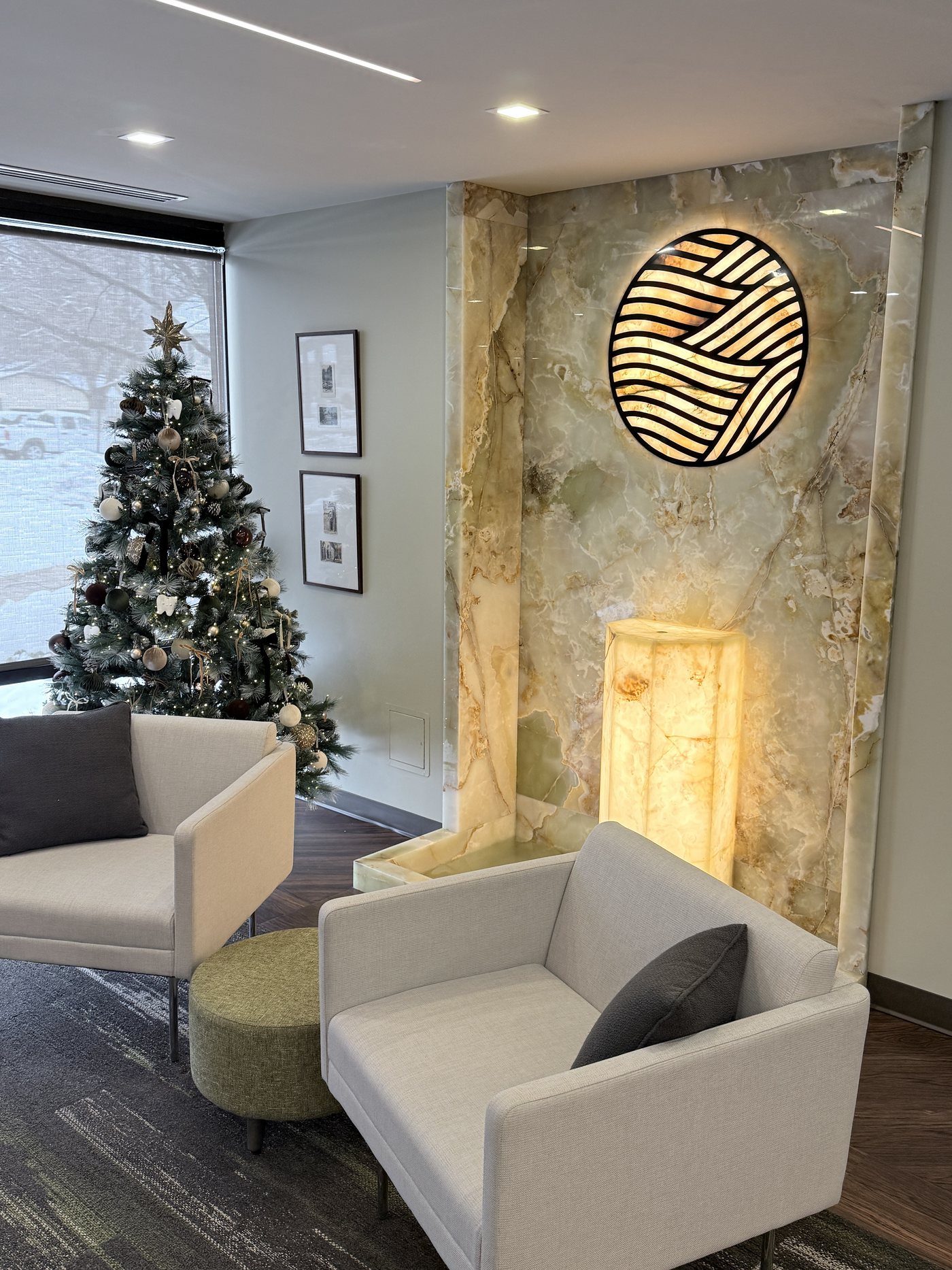 The Refined lounge, with cream armchairs, a stone feature wall, and the illuminated emblem